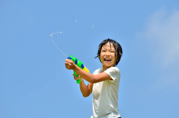 Girl playing with water gun (blue sky)
