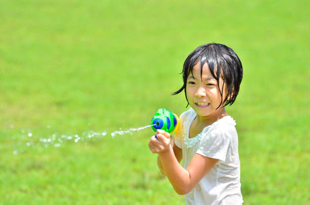 Girl playing with water gun (lawn square)