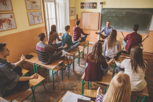 istock Teacher and group of students practicing Yoga in the classroom. 680447446