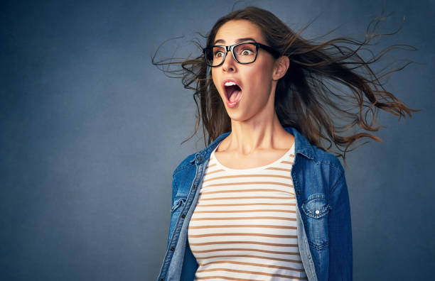 Surprise! Shot of a happy young woman with air being blown in her face in studio gasping stock pictures, royalty-free photos & images