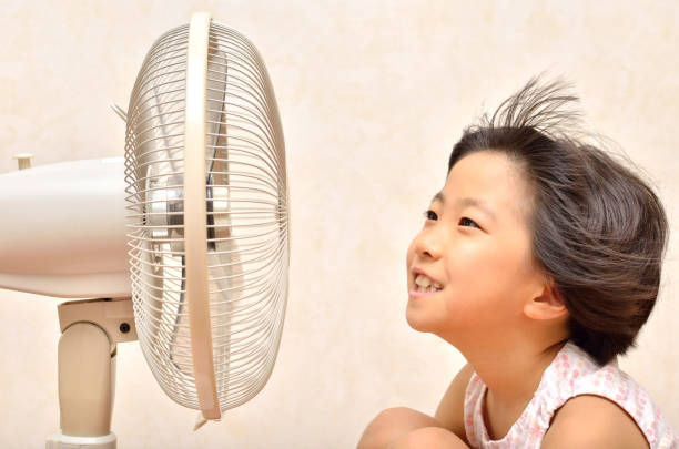 istock Girl cools off with a fan 680465526
