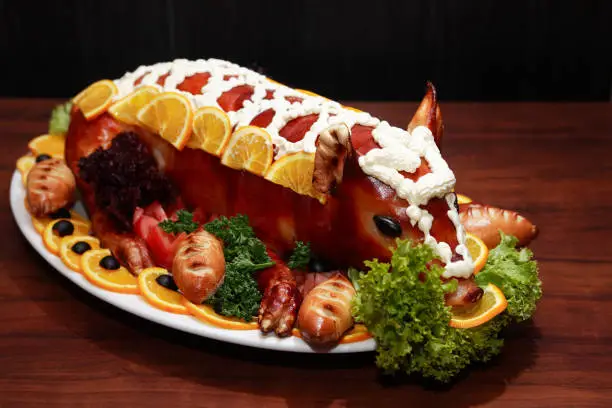 Roast suckling pig decoration with vegetables on big plate