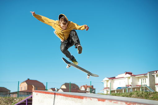 Un skater adolescente hace un truco flip en un skatepark en las afueras de la ciudad photo