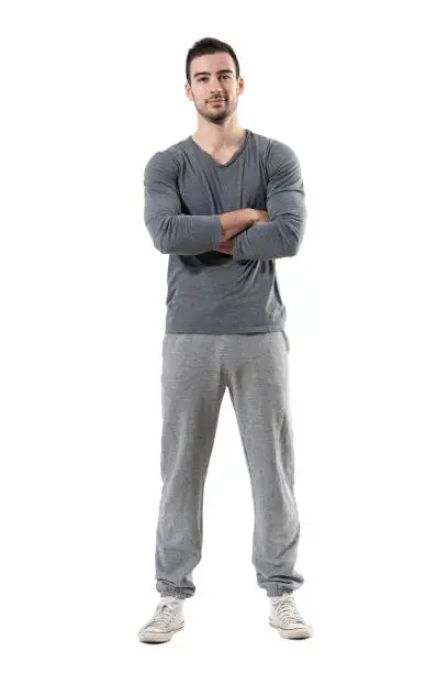 Positive smiling young fit sporty man with crossed arms looking at camera. Full body length portrait isolated on white studio background.