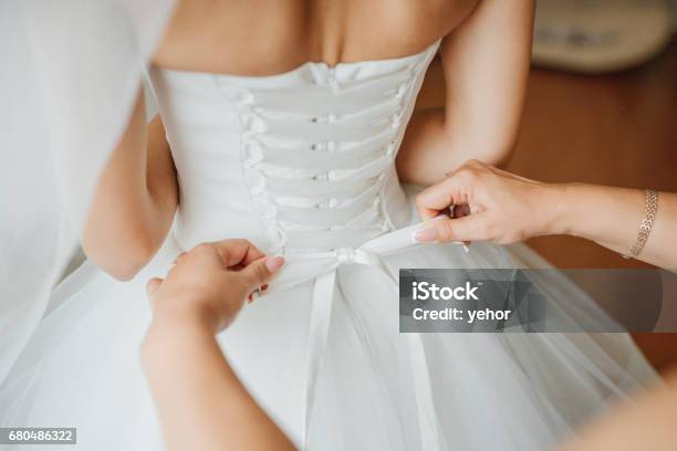 Brautjungfer Macht Bogenknoten Auf Dem Rücken Des Brautkleides Stockfoto und mehr Bilder von Hochzeitskleid