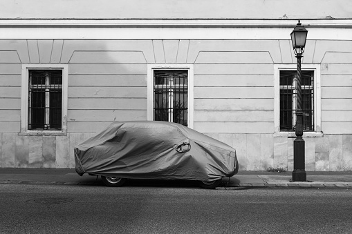 Car covered with textile cover in the street
