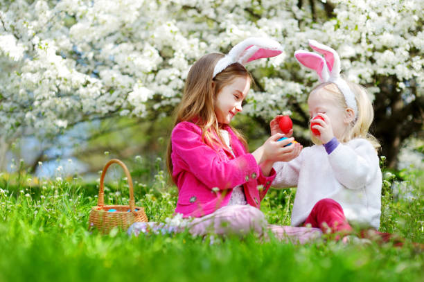 istock Two adorable little sisters hunting for easter egg in blooming spring garden 680497726