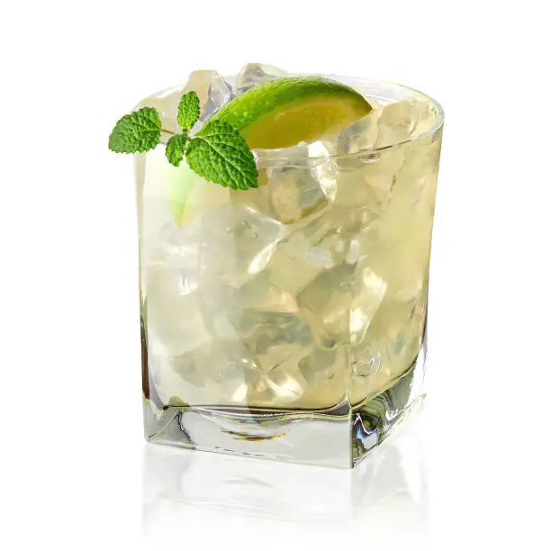 Caipirinha cocktail with lime wedge in rocks glass on log with white background