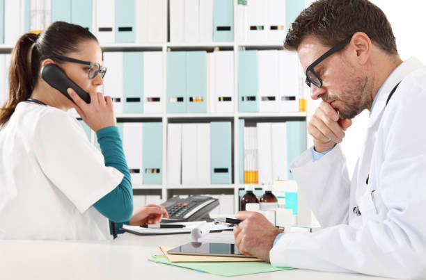 Doctor with the tablet and nurse at phone in medical office Doctor with the tablet and nurse at phone in medical office replay photos stock pictures, royalty-free photos & images