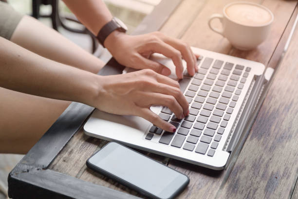istock woman hands on laptop with mobile phone and coffee 680515914