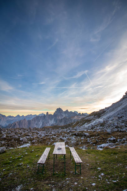 Picnic bench in stunning alpine scenery at sunset. The mountain in the background is Monte Cristallo, Italian Dolomites. stock photo