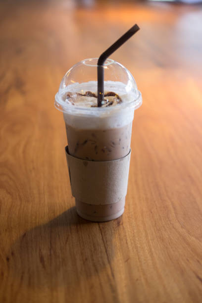 istock Iced coffee  with Ice in plastic cup in the morning light on wood table 680548146