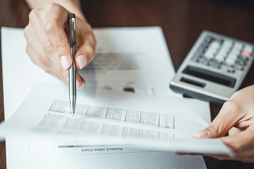 Close up of businesswomans hand with pen doing some financial calculations