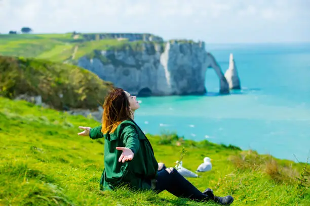 photo of beautiful young woman sitting on the grass and relaxing on the wonderful landmark background