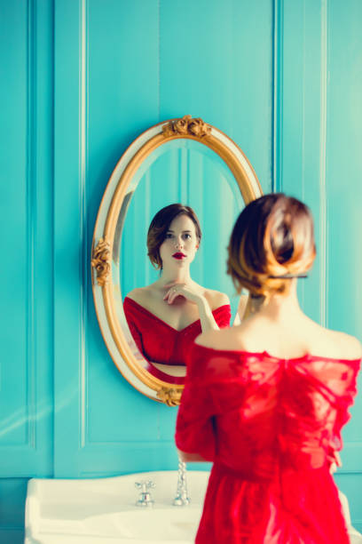 istock young woman looking at mirror 680675738