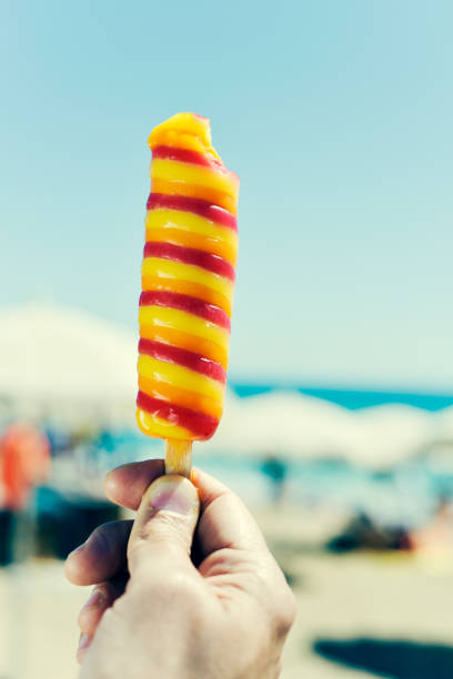 istock man eating a popsicle on the beach 680676210