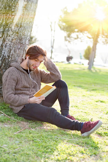 istock Young man reading book in the park 680687700