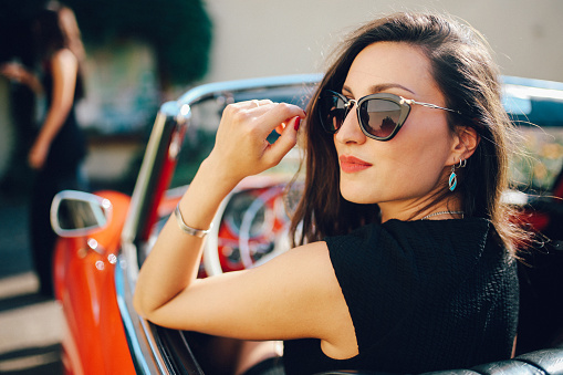 Young fashionable girl in an oldtimer convertible sportscar, in German Baden Wuerttemberg region, near Freiburg.