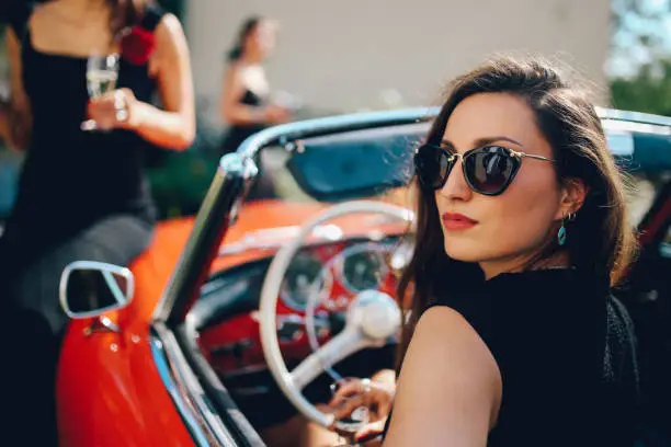 Young fashionable girl in an oldtimer convertible sportscar, in German Baden Wuerttemberg region, near Freiburg.