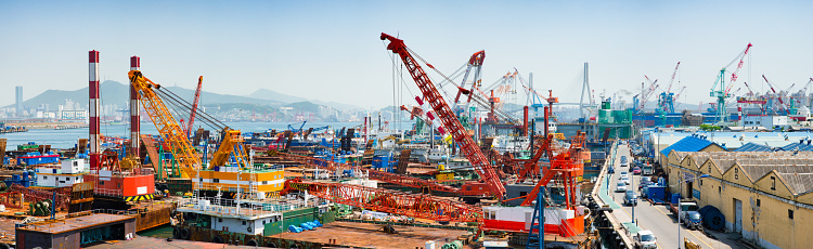 Busan Yeongdo-gu industrial port harbor skyline panorama with multiple loading cranes and hangars