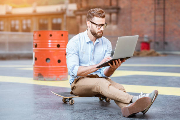 hipster arbeiten mit laptop auf dem dach - skateboard skateboarding outdoors sports equipment stock-fotos und bilder