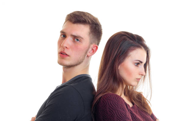 istock young serious guy with a girl stand each other back close-up 680717332