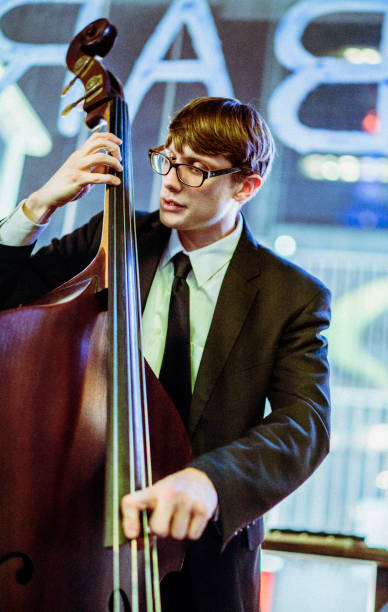 Young old-fashioned looking man wearing eyeglasses playing bass