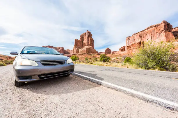 Car parked along road in Arches National Park with red rock canyons