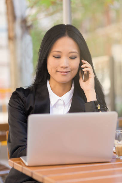 istock Asian cheerful middle-aged businesswoman working at a cafe table 680734468