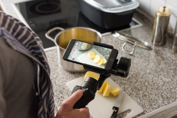 Blogger making smartphone video while cooking stock photo