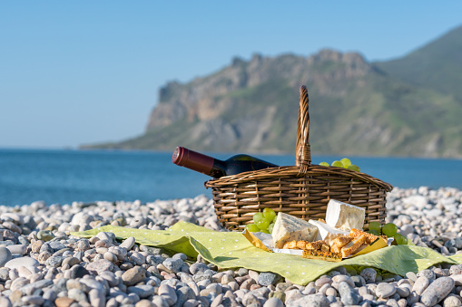 Picnic basket with wine, cheese and grapes on a sea beach