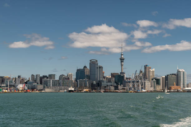 Downtown Auckland skyline seen from harbor. Auckland, New Zealand - March 3, 2017: Wide shot of the city skyline seen from greenish ocean water under blue sky with some white clouds. Highrises, boats and specific buildings. ferry terminal audio stock pictures, royalty-free photos & images