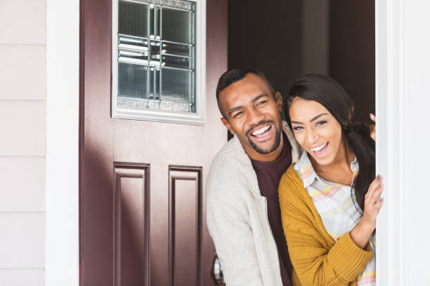 istock Young mixed race couple standing in front doorway laughing 680789092