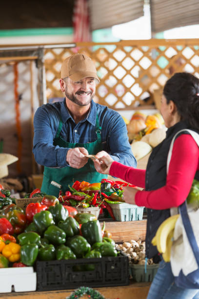istock Man working at farmer's market taking cash from customer 680790132