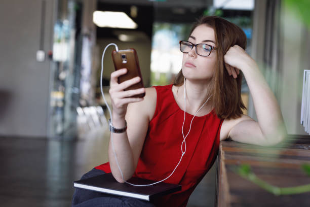 istock Creative Female Student with textbooks listening to music and texting 680794924