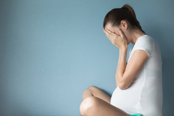 Sad and stressed pregnant woman Stressed pregnant woman against blue background. unwanted pregnancy stock pictures, royalty-free photos & images