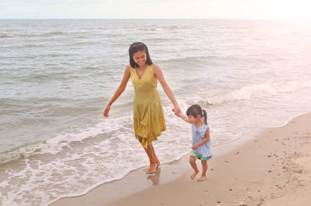 istock Mother and little daughter walking on the beach. 680826280