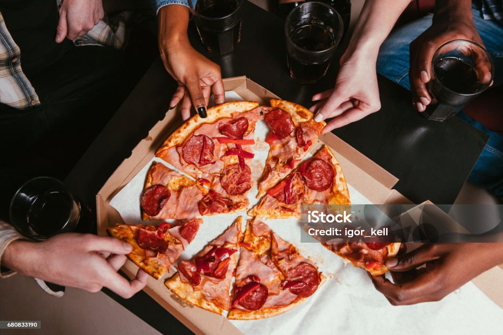 Four friends company eat fresh pizza at home Friends Company Salami Pizza Eat Home Leisure Fun People Unrecognizable Interracial Salami Unhealthy Food Concept Pizza Stock Photo