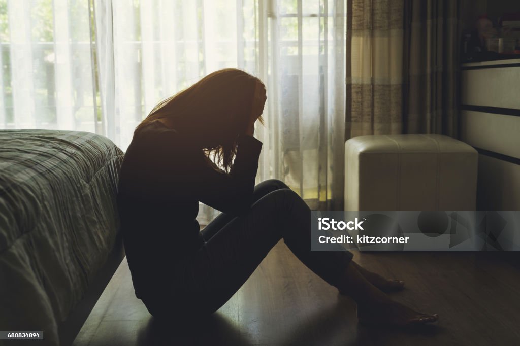 depressed woman sitting in the dark bedroom depressed woman sitting head in hands in the dark bedroom Depression - Sadness Stock Photo