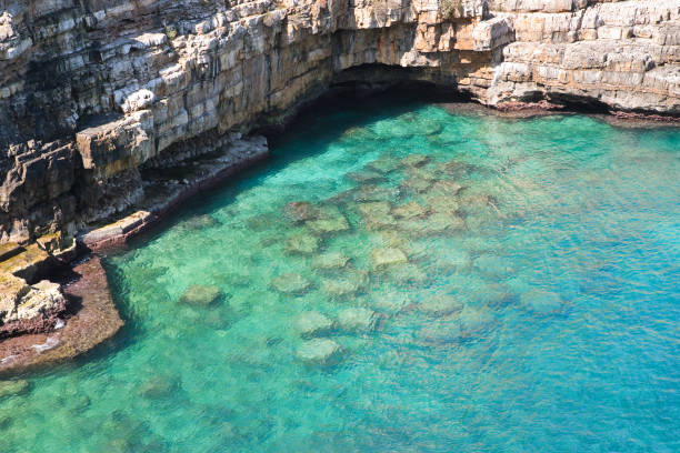 Polignano a Mare, Italy - June 21, 2019 Village on a steep cliff and people swimming