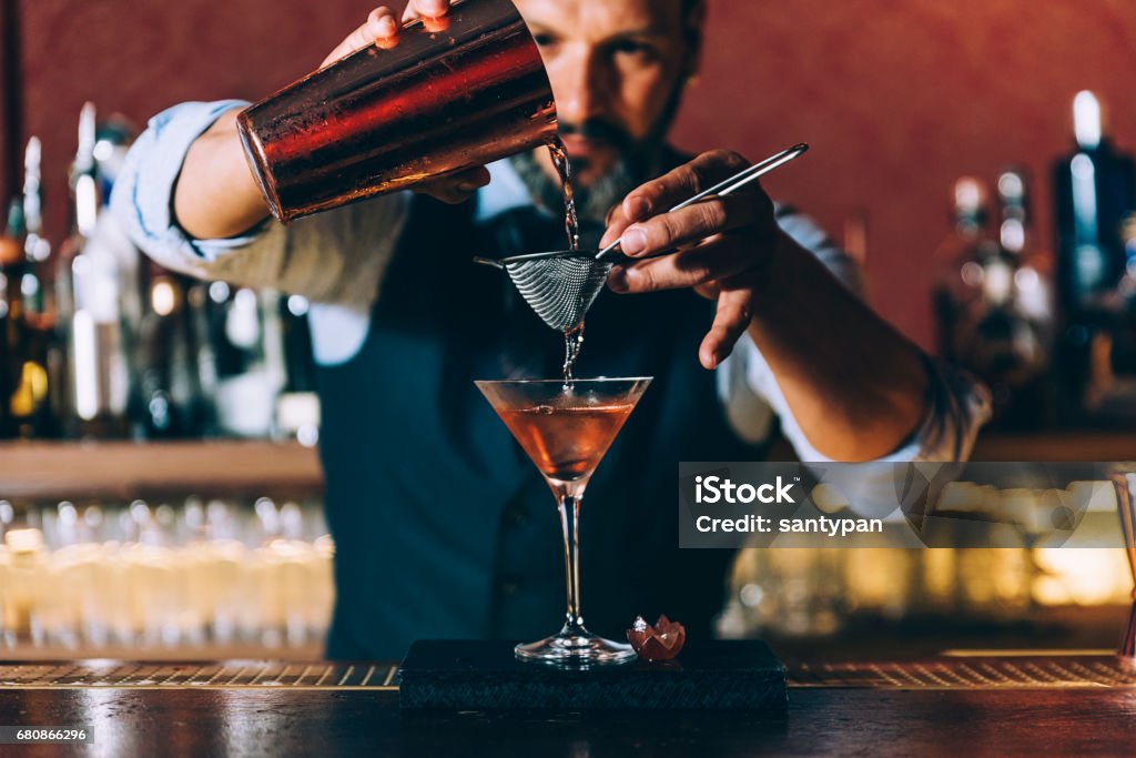 Barman is making cocktail at night club. Expert barman is making cocktail at night club. Bartender Stock Photo