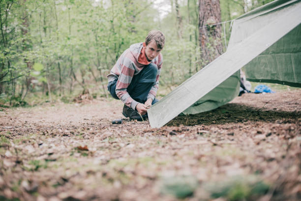 istock Tourist setting up a tent in spring forest. 680873722