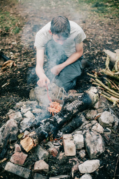 istock Wayfarer stirring meal in frying pan on campfire. 680873784