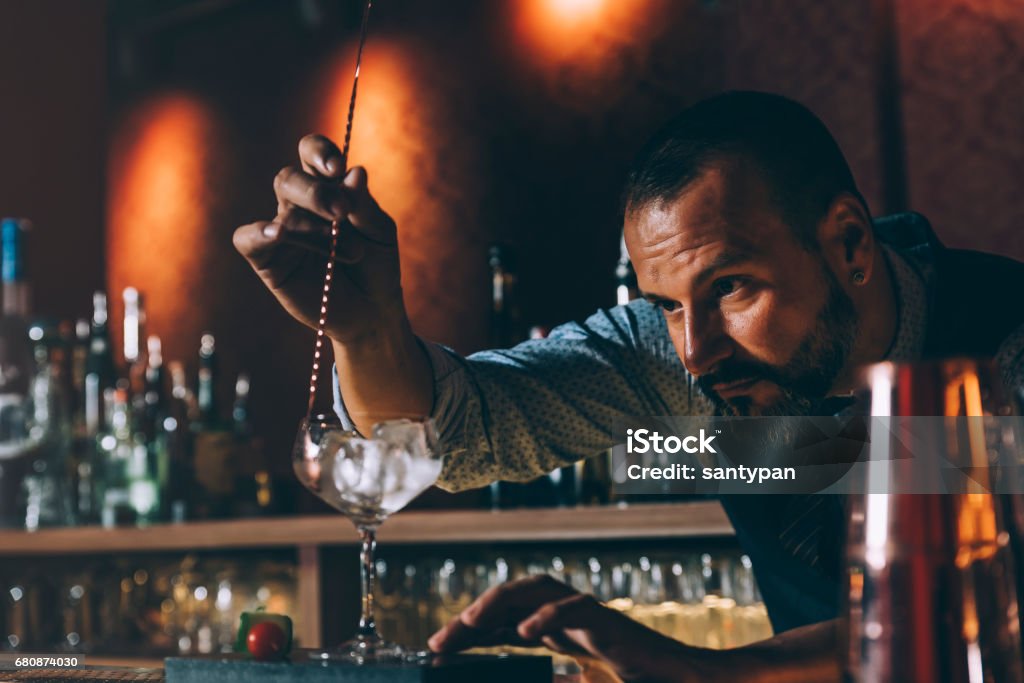 Barman is making cocktail at night club. Expert barman is making cocktail at night club. Bartender Stock Photo