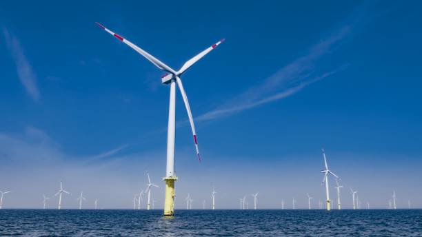 Offshore wind farm Wind turbines spinning in sea against blue sky. offshore wind farm stock pictures, royalty-free photos & images