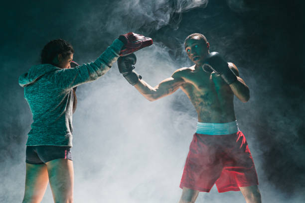 istock Handsome Afro American boxer with bare torso is practicing punches with a partner at the fight club 680882810