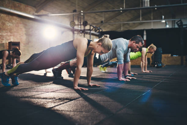 gruppe von erwachsenen tun push-up-übungen - athlete push ups muscular build female stock-fotos und bilder