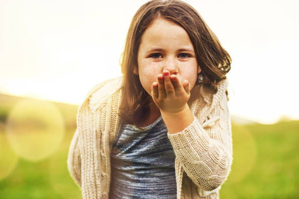 Portrait of a sweet little girl blowing a kiss while standing outside