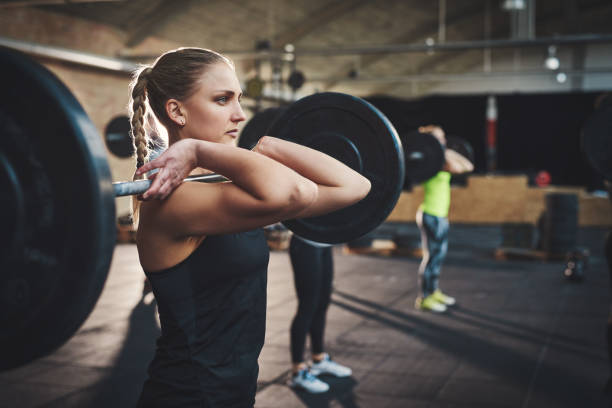 istock Woman pulling up large barbell in fitness class 680886664
