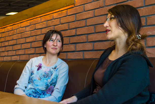 istock Two brunette young women sitting in a cafe having conversation 680888274